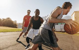 Active men playing basketball outdoors, representing a return to sport after arthroscopic knee surgery recovery at Tyrance Orthopedics in Delray Beach.