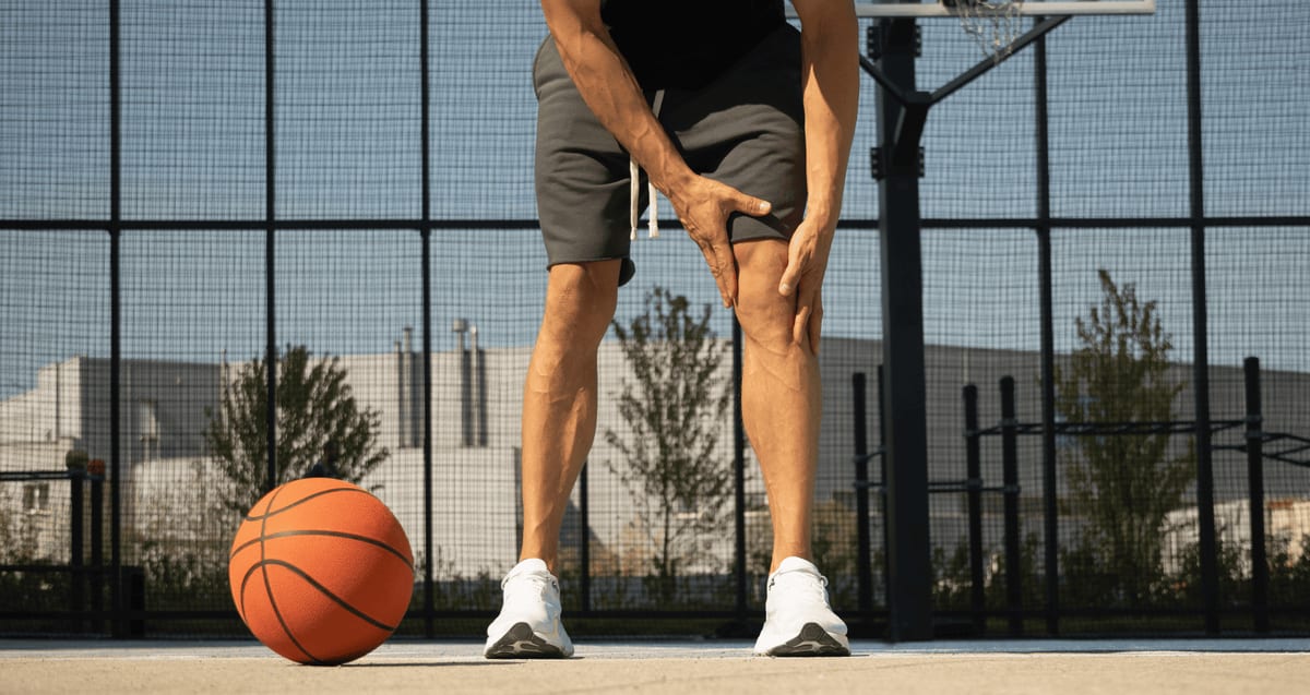 Basketball player on an outdoor court gripping his knee in pain, a common sign of a meniscus tear treated without surgery at Tyrance Orthopedics in Palm Beach.