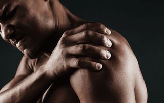 Man grimacing while gripping his painful shoulder, a sign of a rotator cuff injury treated with PRP therapy at Tyrance Orthopedics in Delray Beach.