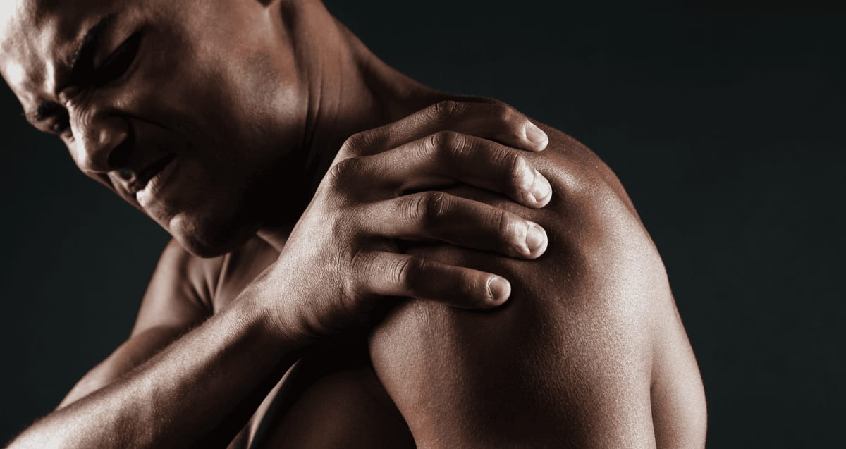Man grimacing while gripping his painful shoulder, a sign of a rotator cuff injury treated with PRP therapy at Tyrance Orthopedics in Delray Beach.