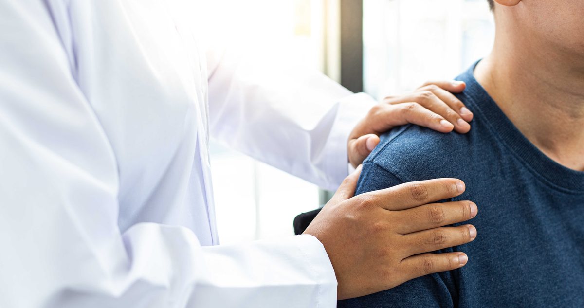 Person pointing to pain on top of the shoulder at the AC joint during an arthritis evaluation.