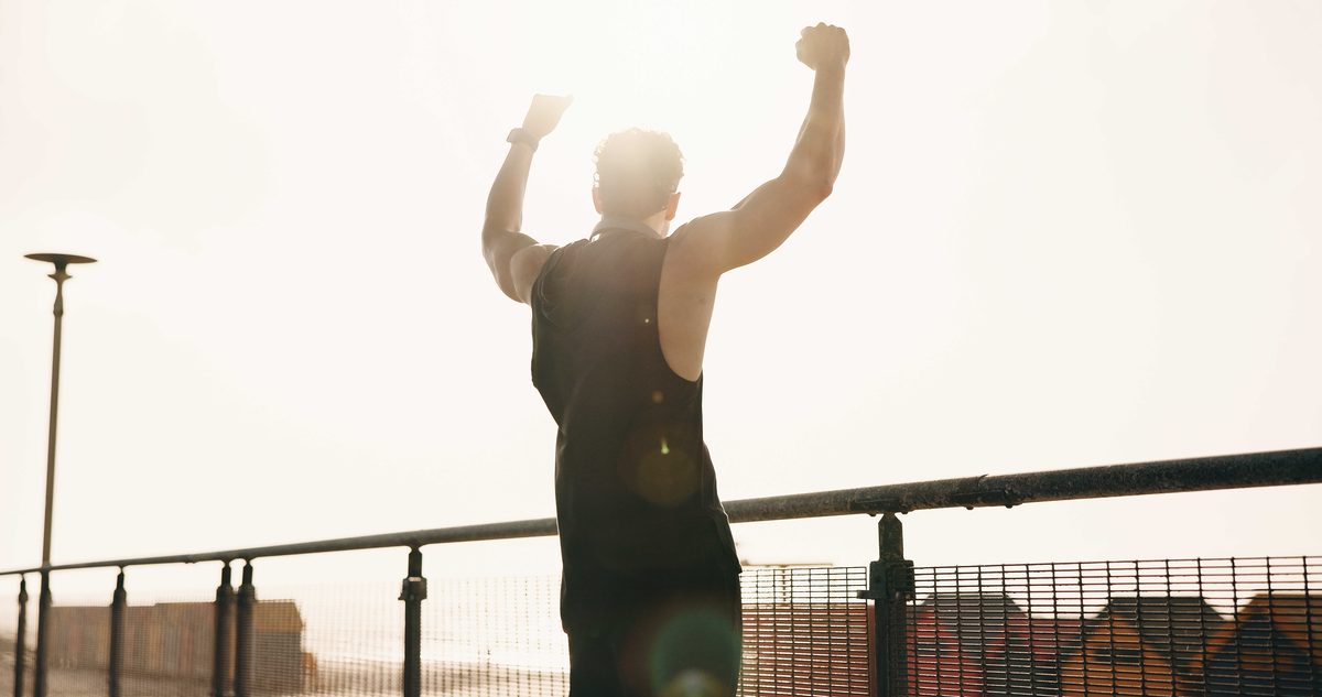 Rotator Cuff Surgery Recovery: What Delray Beach Patients Can Expect Man raising both arms on a waterfront path at sunrise, the overhead reach a repaired rotator cuff is meant to give back.