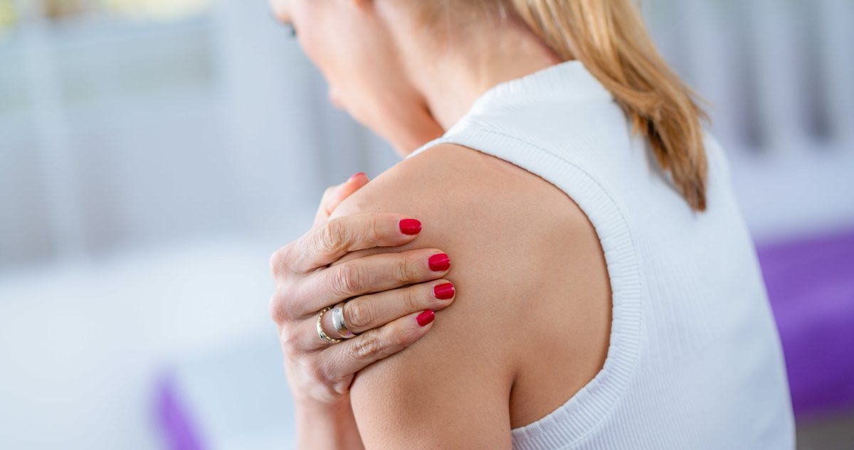 Shoulder Osteoarthritis Treatment Options Woman resting a hand on an aching shoulder, the deep ache and stiffness shoulder osteoarthritis brings on with movement.