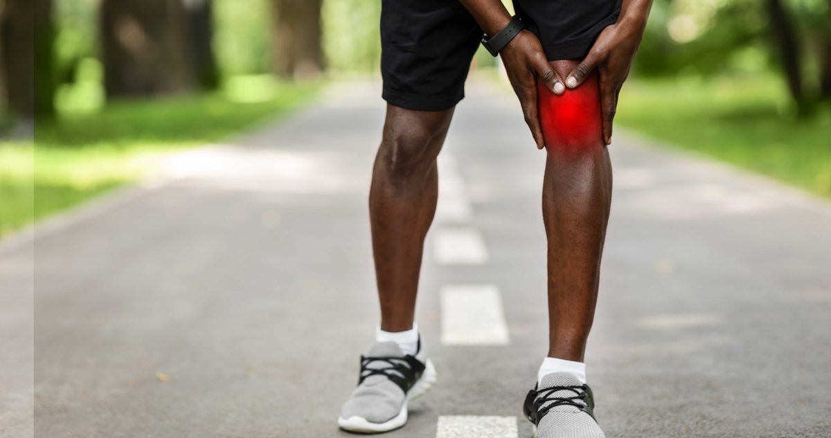 When to See a Sports Medicine Doctor Runner stopping on the road to hold a knee flagged in red, the point at which a sports medicine visit is worth making.