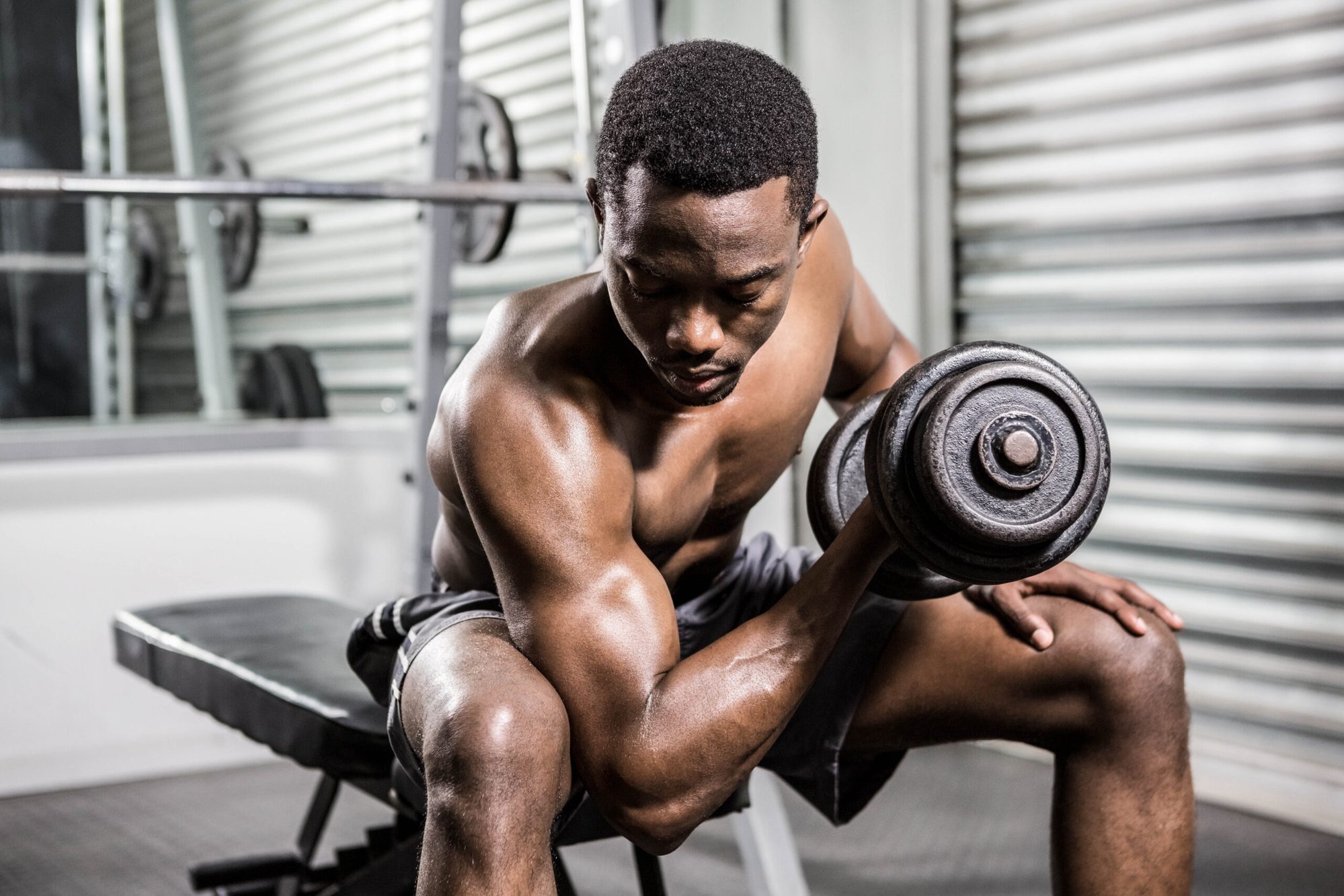 Shirtless man lifting dumbbell on bench at the crossfit gym Stem Cells, Delray Beach, Tyrance Orthopedics